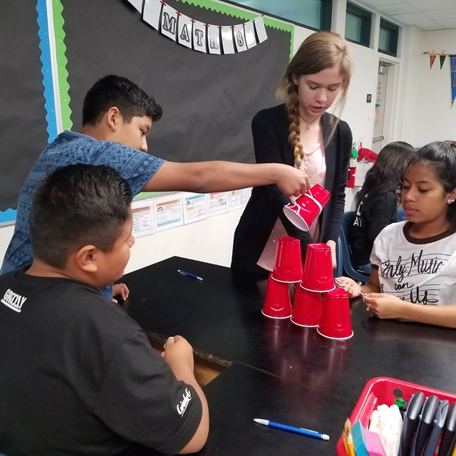 Students prepare to engage in a new experiment where they first have to stack cups together.